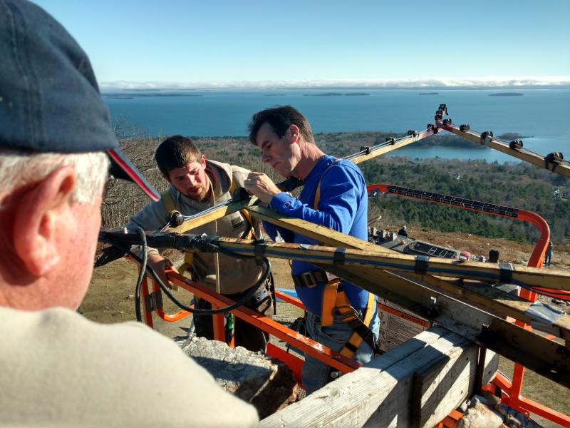 Tom Jackson, Simon Derico and Randy Stearns get the Mt. Battie Star in place high over Camden Harbor and Penobscot Bay, Nov. 19. (Photo courtesy David Walck)