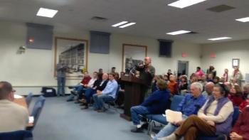 The organizer of a petition against the concept plan speaks from the podium.