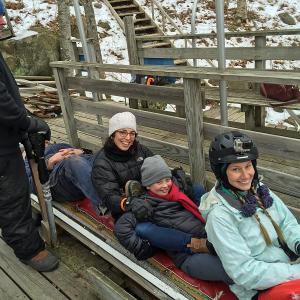 Bangor Daily News outdoor reporter Aislinn Sarnacki sits at the front of the toboggan Jan. 29, with Cute Potato blogger Jen Hazard and her daughter sandwiched in the middle. At the back, for ballast, is Toboggan Committee member and veteran racer Jim Jefferson, while Chute Master Stuart Young stands at the ready to release the sled into the chute. (Photo by Holly S. Edwards)
