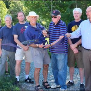 Holding the giant scissors, Camden-Rockport Pathways Committee Chairman Geoff Scott, left, and Camden Select Board member Don White, right, cut the ribbon officially marking completion of the Seabright section of the Camden Riverwalk. (Photos by Chris Wolf)