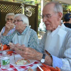 Quarry Hill residents Jane Fairbanks (obscured) and Marnie and Alan Pease enjoy the community’s lobster bake, held August 18. (Photo courtesy of Quarry Hill)