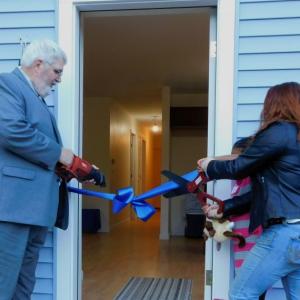 Brandi Brown (right) cuts the ceremonial ribbon with the help of Randy Mailloux, the board president of Habitat for Humanity of Waldo County. (photo by Erica Thoms)
