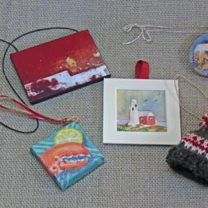 A sample of the charming ornaments for sale at the Kefauver Studio & Gallery (clockwise from bottom left): oil by Will Kefauver, double-sided photograph by Sherie Lehman, “chipadee” by Kathi Nordone, knit hat by Justine Kefauver, and (center) watercolor by Kathleen Horst.