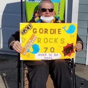 Gordie Guist, of Camden, watches a caravan of 30 cars passing by his home, many with canine passengers, who surprised him with a drive-by celebration on his 70th birthday April 19. (Photo courtesy of Robin Guist)