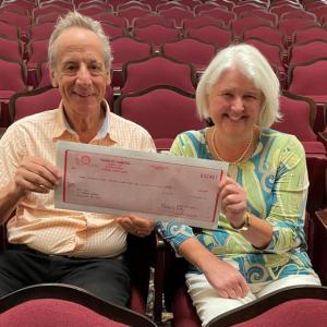 ‘Bingo Queen’ producer John Burstein presents a check for $3,892.50 to Liz Schuh, Executive Director of the nonprofit MCH, Inc., at the Camden Opera House, where Burstein’s show to benefit Meals on Wheels was performed July 29 and 30. (photo courtesy of Dave Morrison)