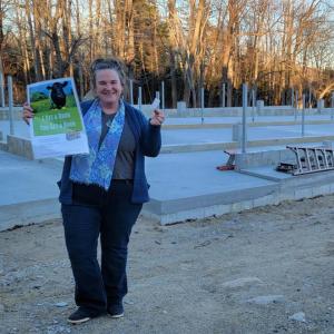 Heidi Baker, General Manager of Aldermere Farm and Erickson Fields Preserves, holds the winning ticket of the Toy Barn Raffle. Baker stands in front of the site of the new educational barn being constructed at Aldermere Farm. (Photo by Joelle Albury)