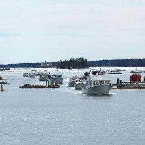 The parade of lobster boats comes through the Boothbay Harbor Footbridge for the very last time. (Photo by Steve Edwards)