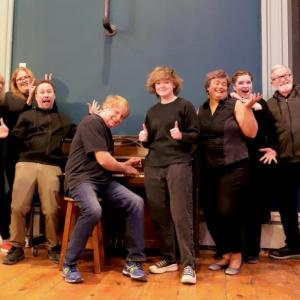 Barrie Quappe, Gwyneth Sauvage, Erik Perkins, Chuck Quappe, Miles Mailloux, Angela Dominichelli, Teri Quappe, and Bob Nichols gather around the piano at the Basil Burwell Community Theater. Photo: Gwyneth Sauvage. (Photo courtesy Belfast Maskers)