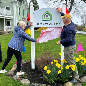 Homeworthy Board Chair Caroline Morong (L) and former Board Member Rich Norman (R) unveil the new Homeworthy sign