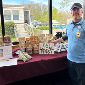 Jason “J” Golla, Pen Bay Nutrition Services food service rep I, stands with the hospital’s new Buy Local food stand. (Photo courtesy Pen Bay Medical Center)