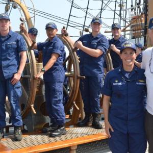 U.S. Coast Guard Academy cadets and Eagle crew members help steer the Eagle into Rockland Harbor, Aug. 2. There are four Coast Guard Academy cadet fourth class selects, and two Eagle crew members behind Captain Jessica Rozzi-Ochs and Maine’s U.S. Senator Angus King. (Photo by Lynda Clancy)